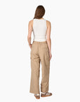 A woman shown from the back wearing beige wide-leg cargo pants, a white sleeveless top, and brown sneakers against a plain white background. 