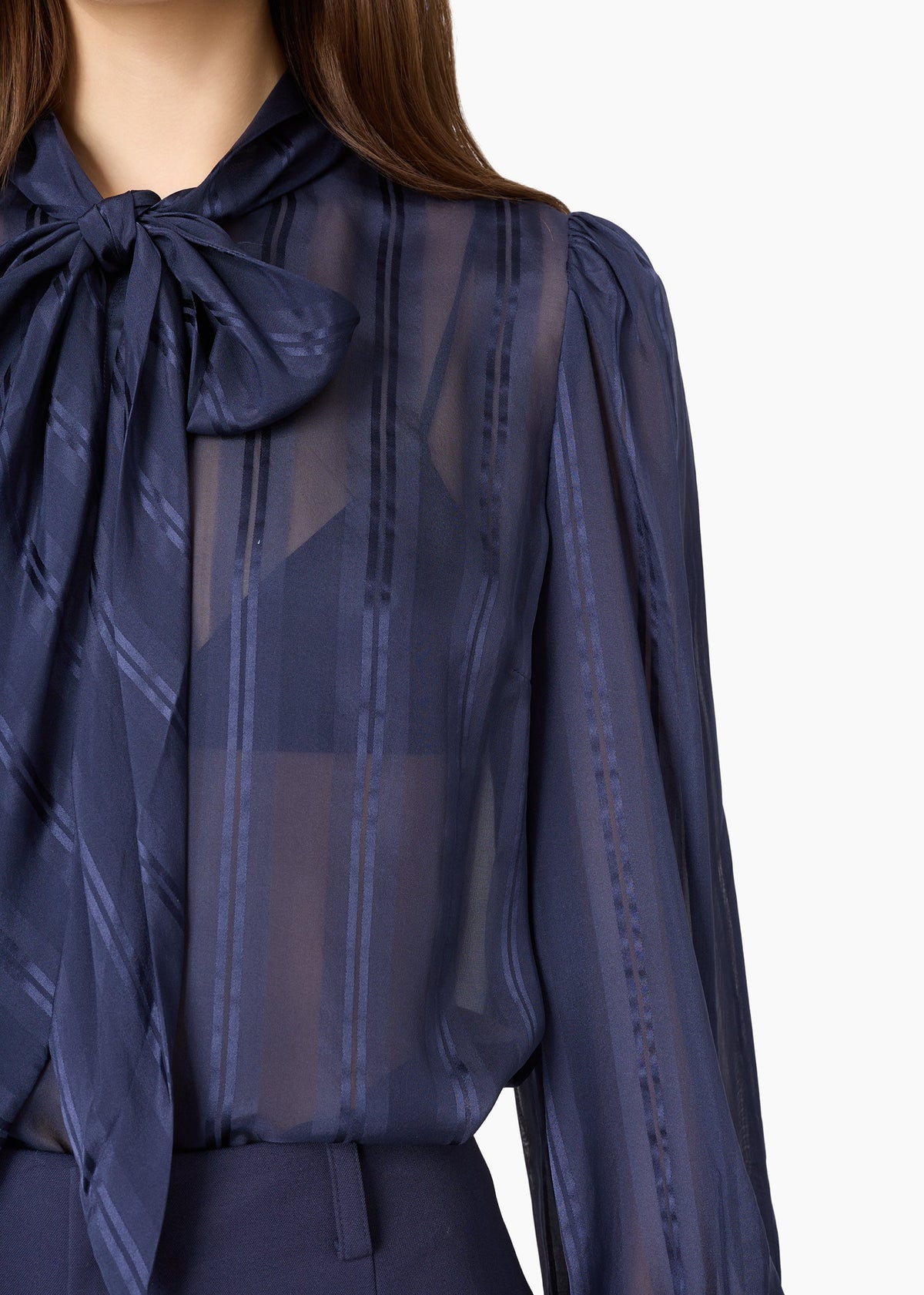 close up of a model wearing a sheer navy top with a tie neck 