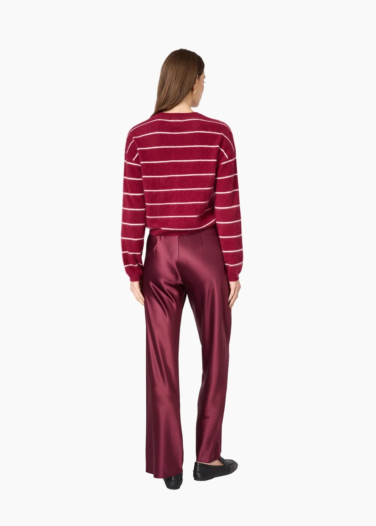 A woman modeling a burgundy cardigan with thin white horizontal stripes and matching satin trousers against a plain white background, back view