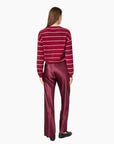 A woman modeling a burgundy cardigan with thin white horizontal stripes and matching satin trousers against a plain white background, back view