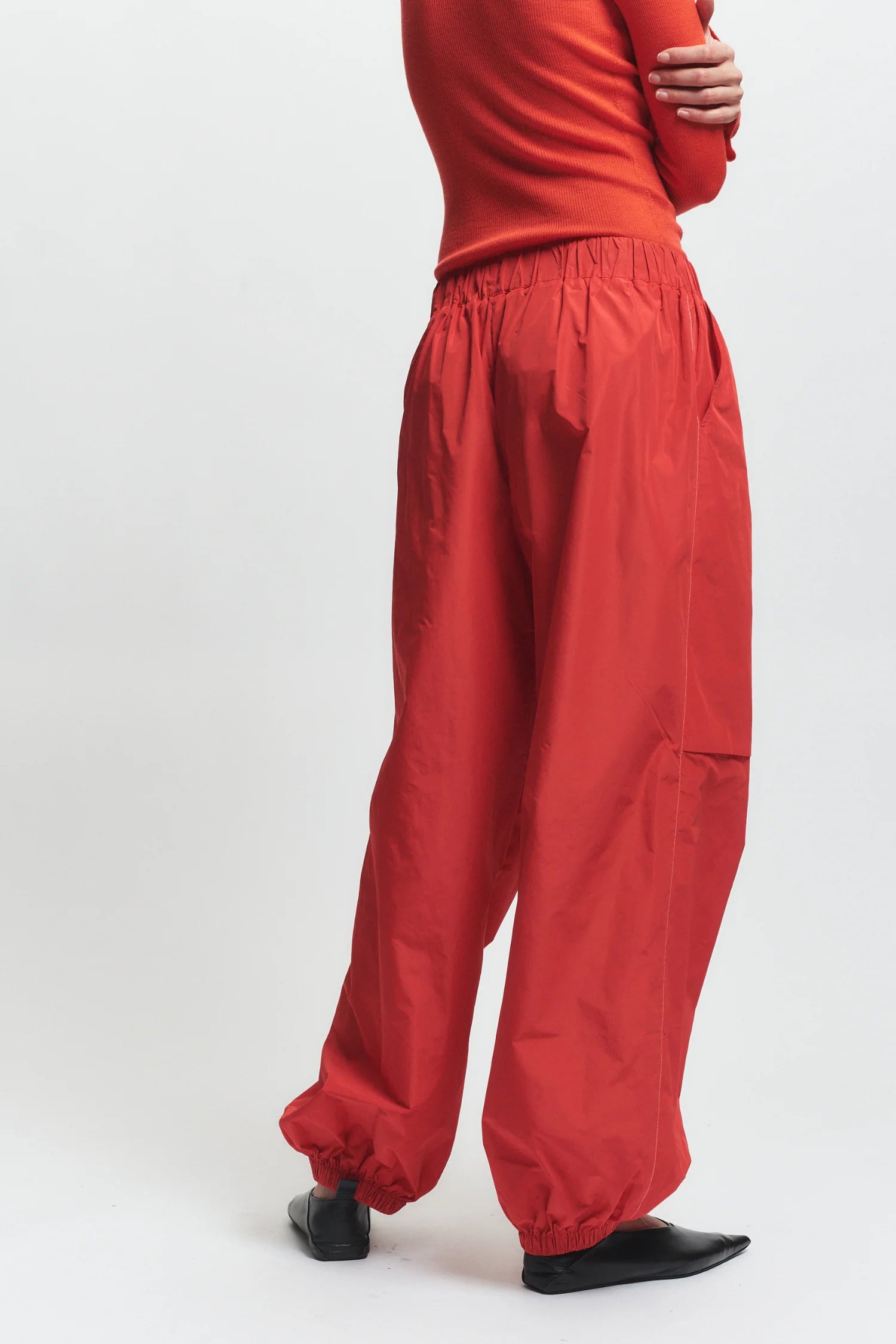 Person wearing red pants and a red top on a white background, back