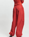 Person wearing red pants and a red top on a white background, back
