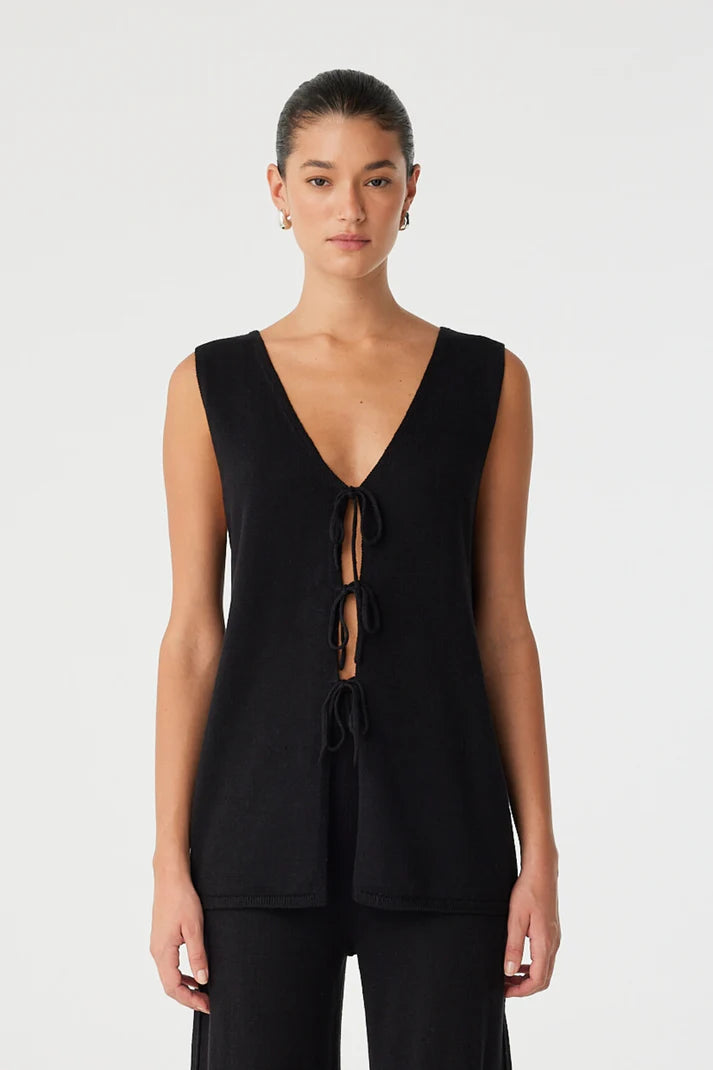 Woman wearing a black sleeveless top with a deep neckline on a white background