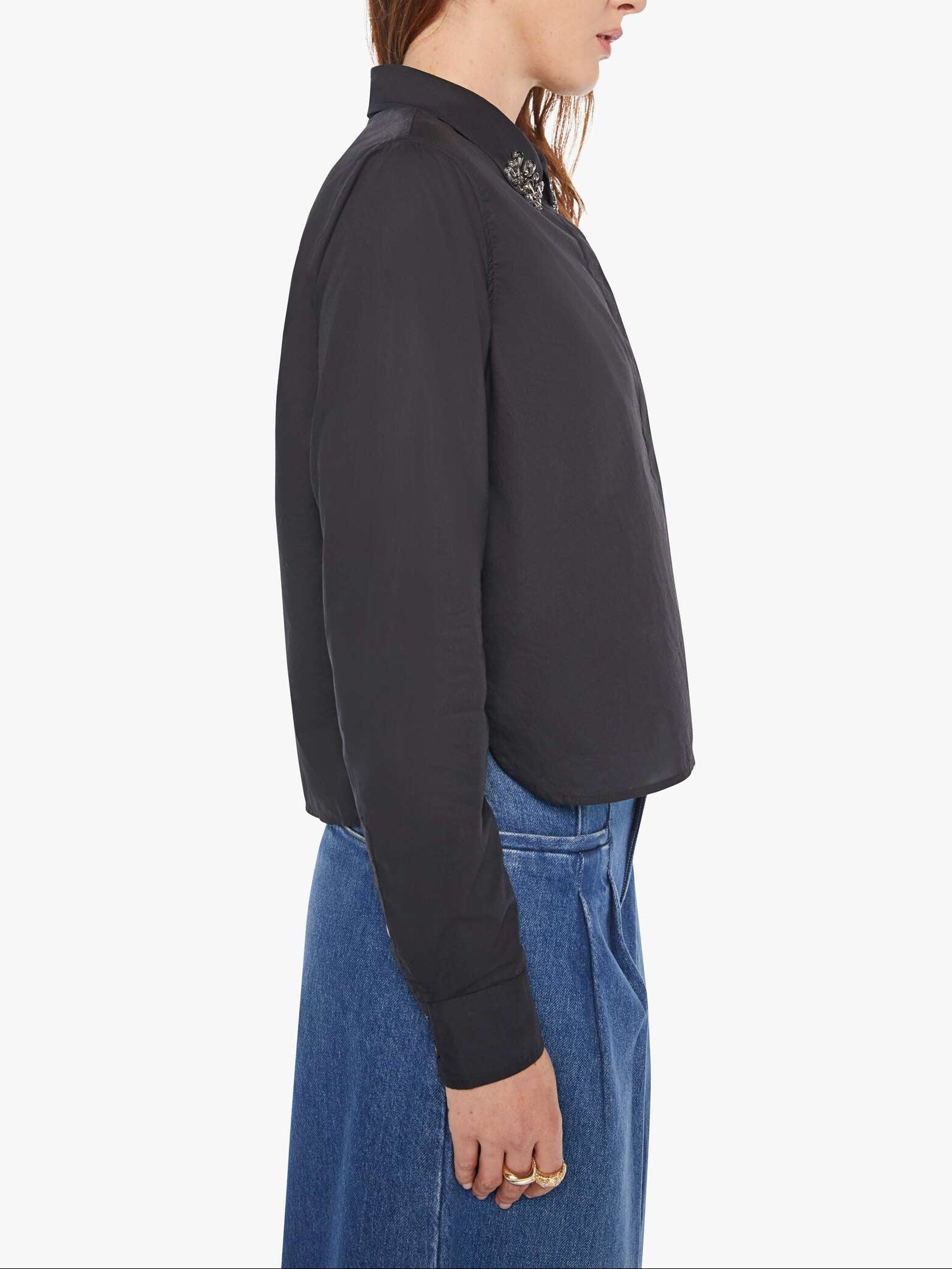 Person wearing a dark gray jacket and blue jeans on a white background