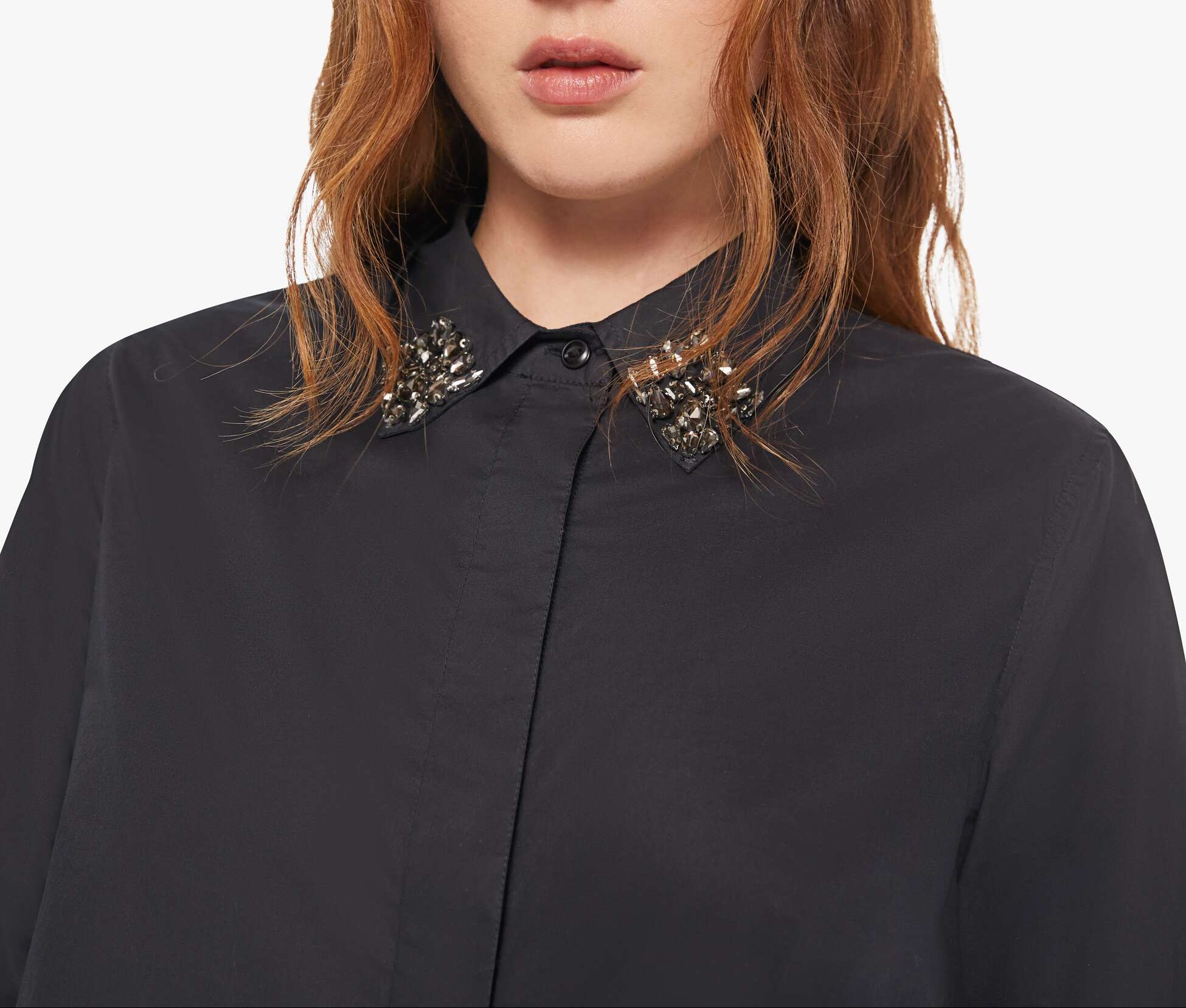 Woman wearing a black shirt with a decorative collar against a white background