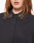 Woman wearing a black shirt with a decorative collar against a white background
