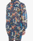 Woman wearing a long, patterned shirt with colorful horse design on a white background