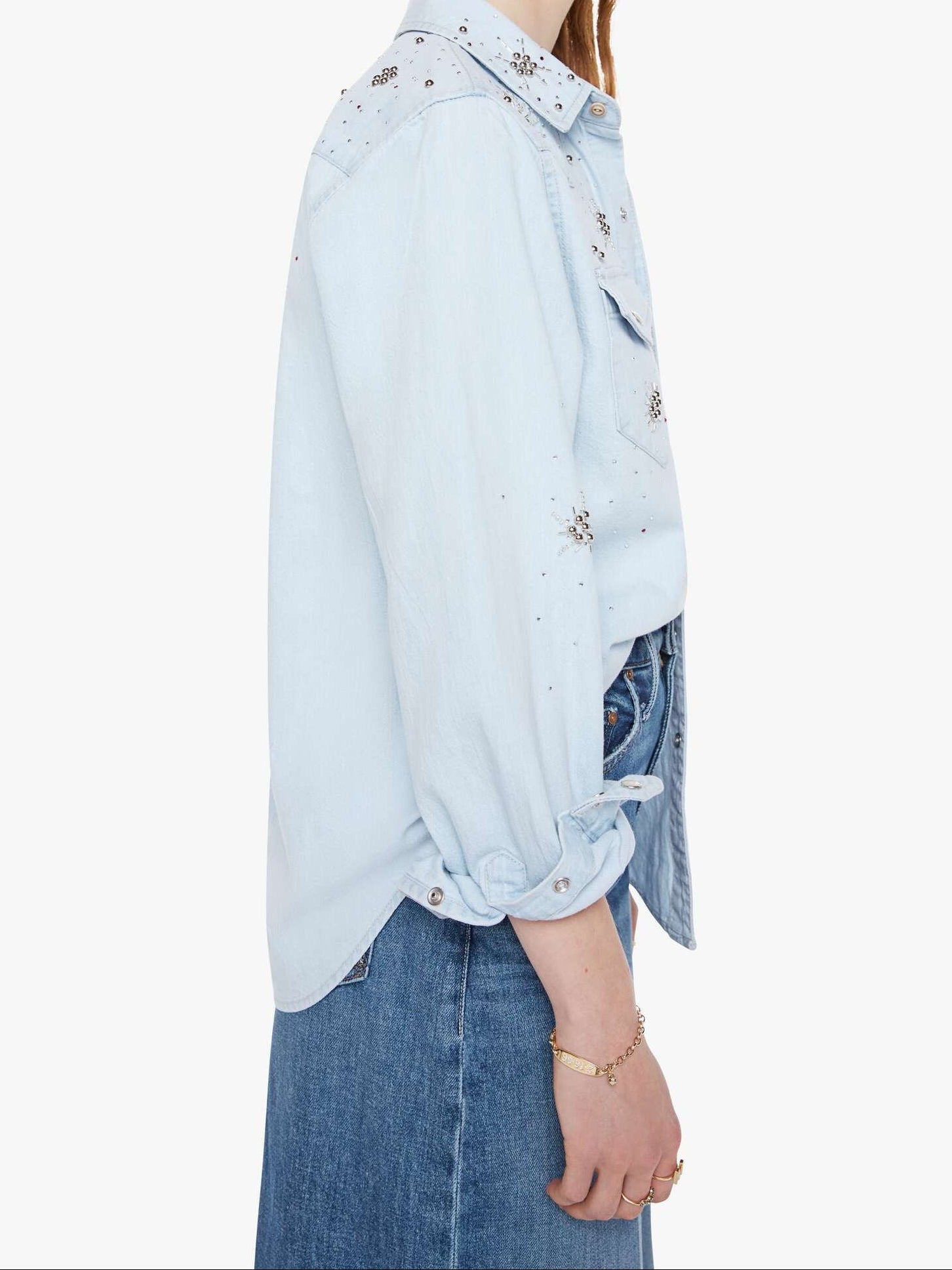 Woman wearing a light blue denim jacket with floral embellishments on a white background