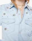 Light blue denim shirt with floral embellishments worn by a model on a white background