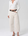 Person wearing a white long-sleeve shirt and beige wide-leg pants on a white background