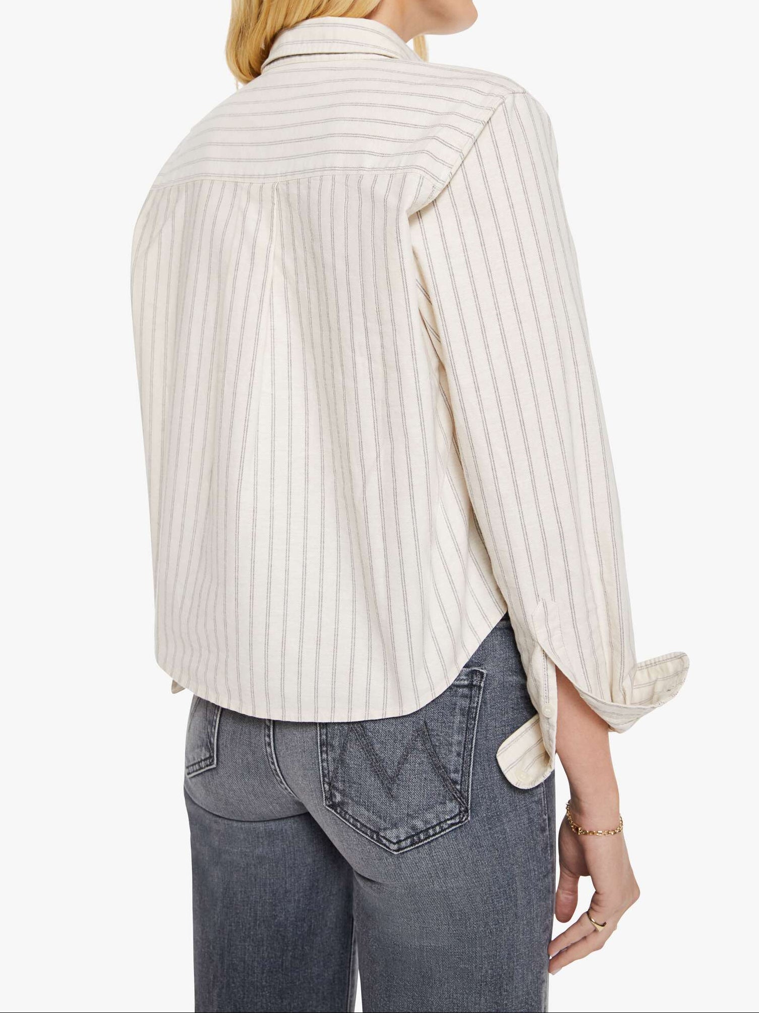 Woman wearing a white striped shirt and gray jeans on a white background