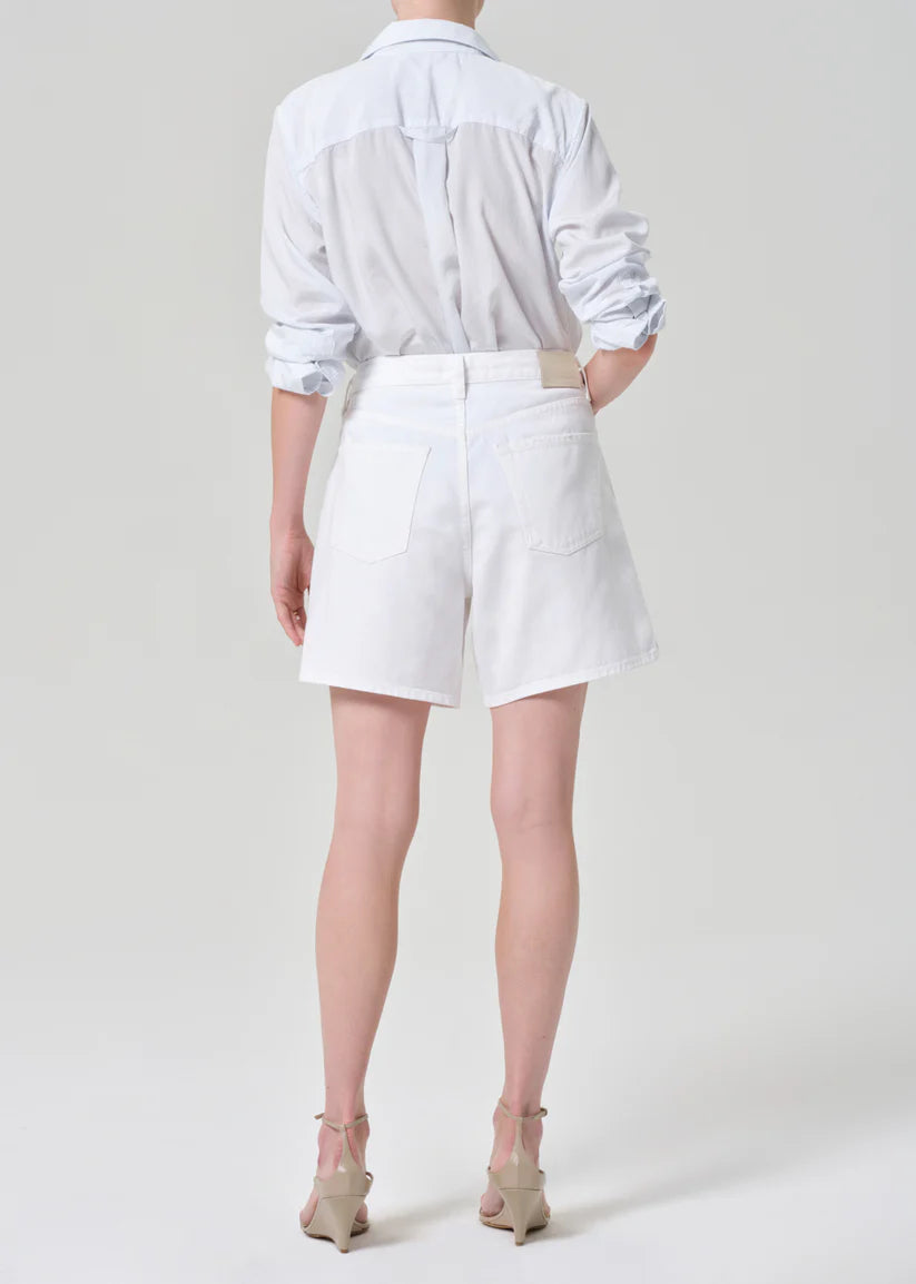 Person wearing a white shirt and white shorts on a plain background