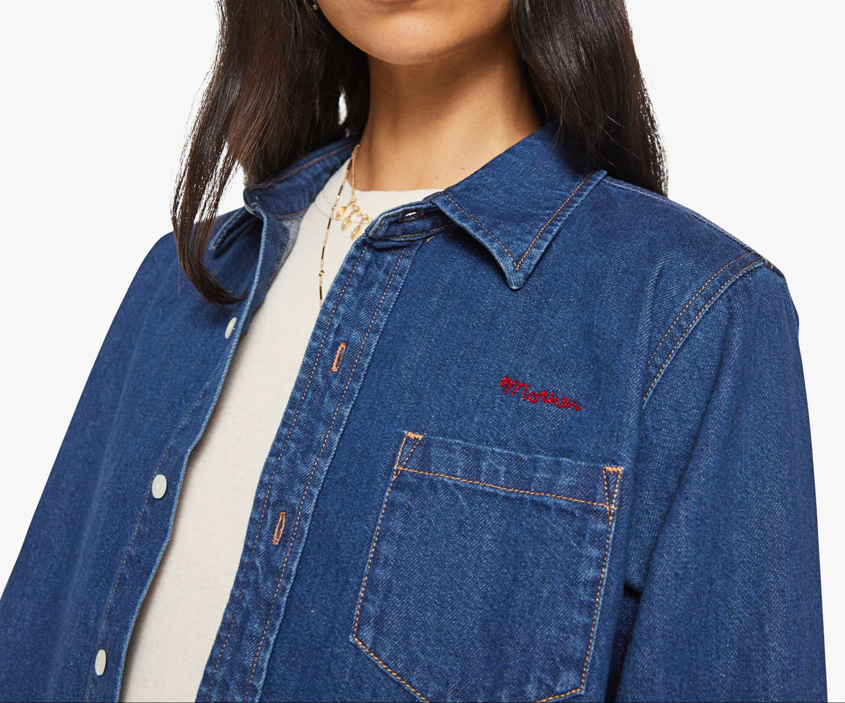 Woman wearing a blue denim jacket with a brand logo on a white background