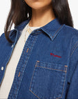 Woman wearing a blue denim jacket with a brand logo on a white background