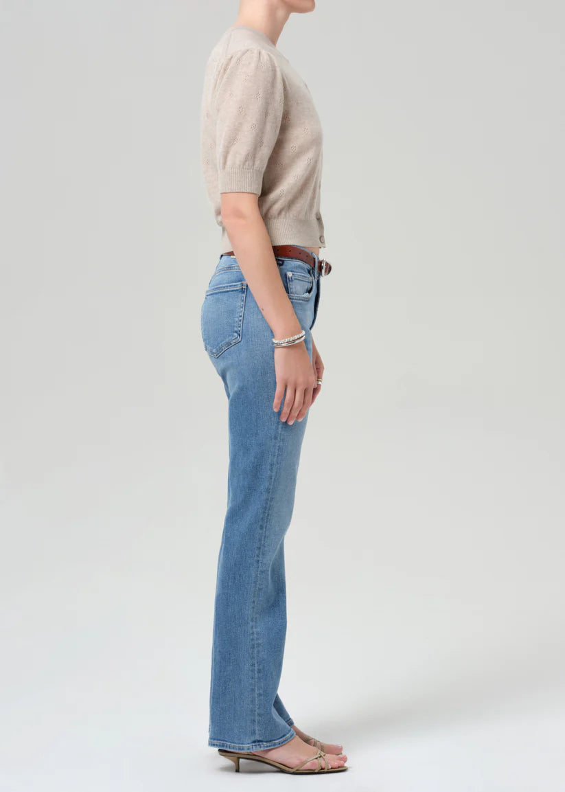 Person wearing a beige sweater and blue jeans on a white background