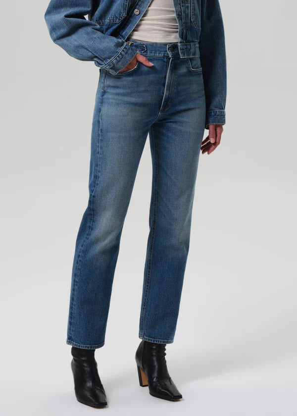 Person wearing blue jeans and a denim jacket on a white background