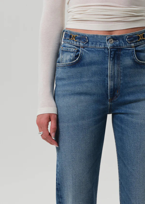 Blue jeans worn by a person on a plain background detail view