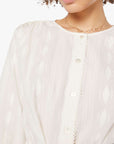 Person wearing a light-colored blouse with a plain background, super close up