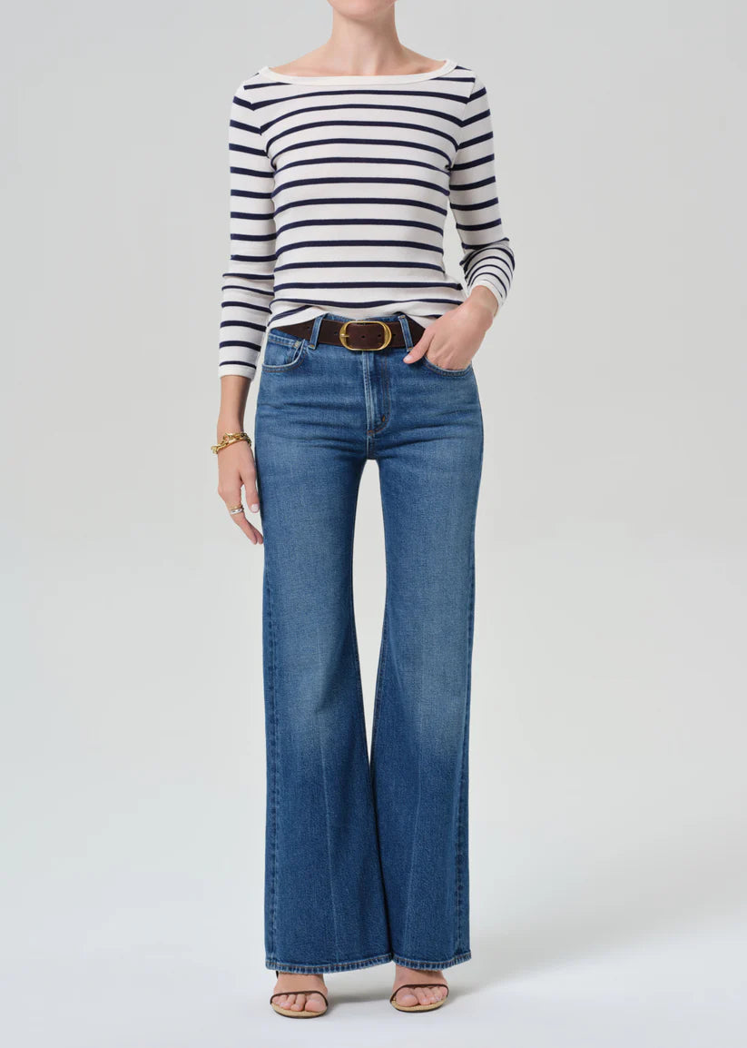 Person wearing a striped shirt and blue jeans on a white background