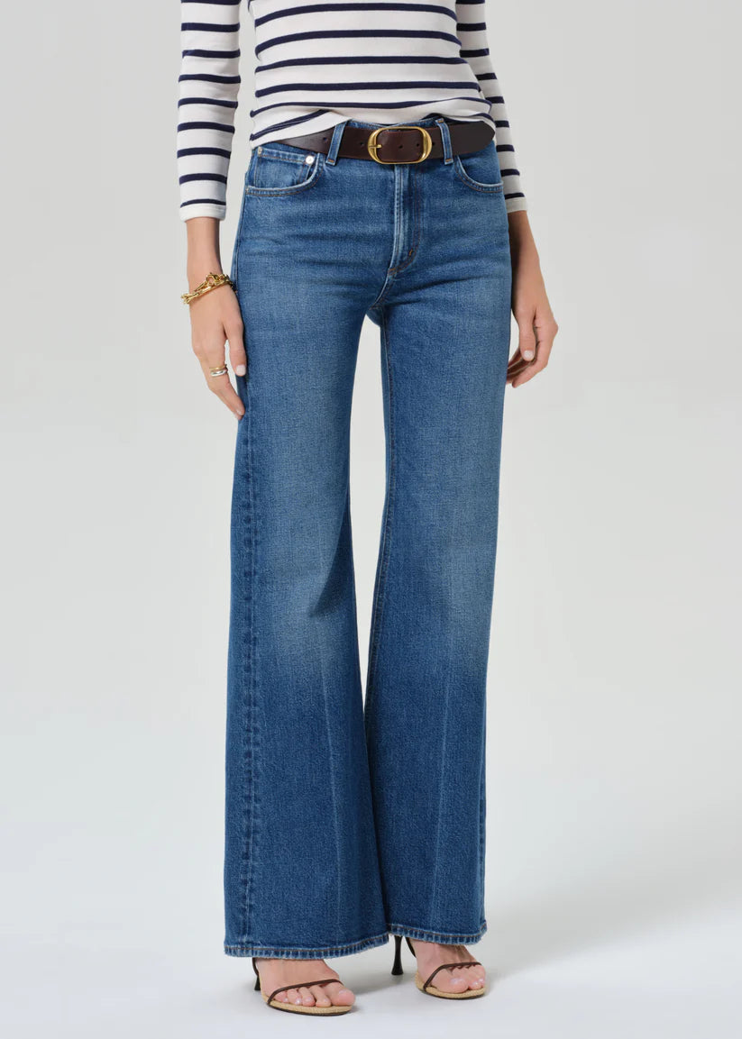 Person wearing blue jeans and a striped shirt on a white background