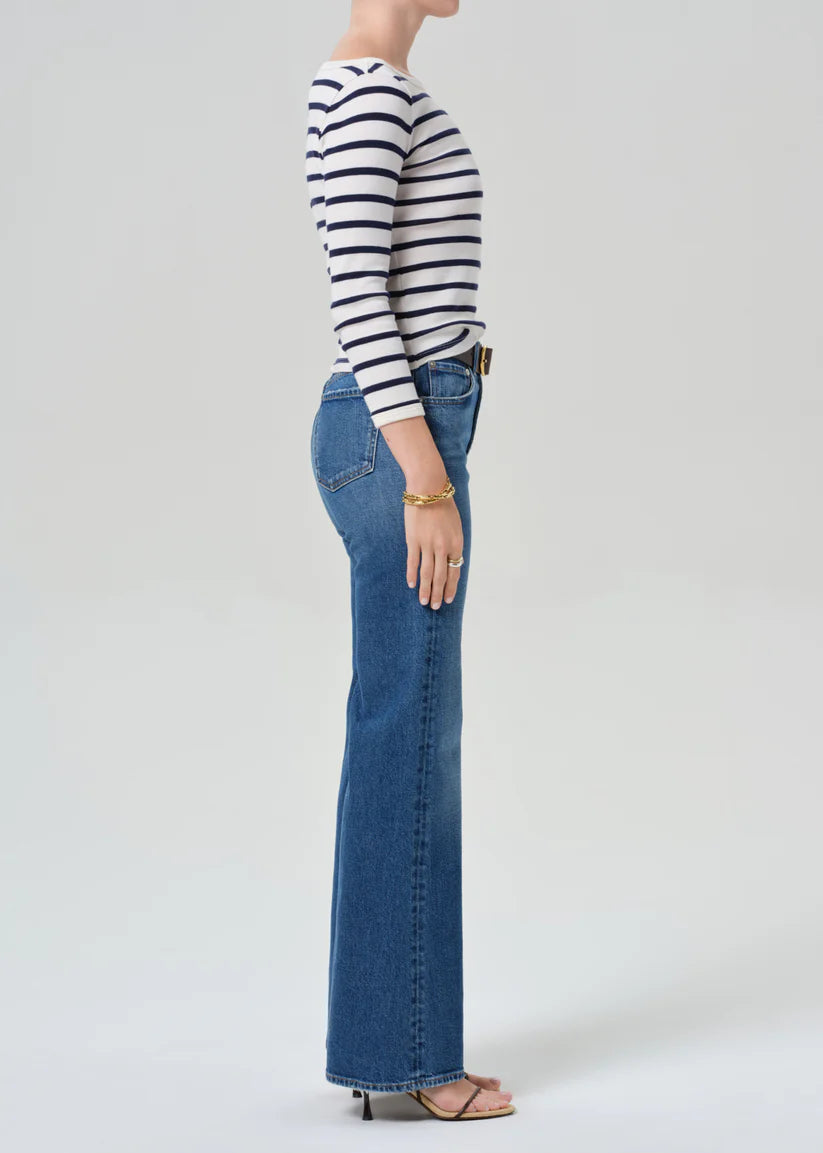 Person wearing a striped shirt and blue jeans on a white background