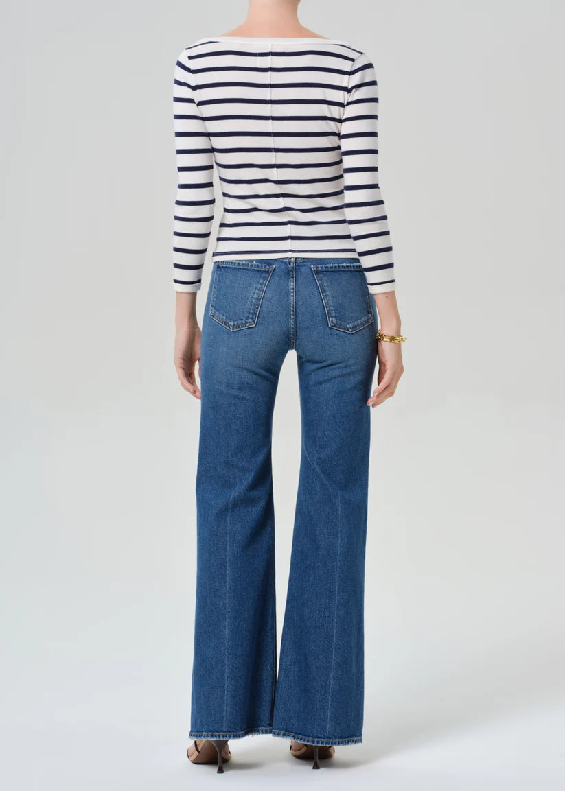 Person wearing a striped shirt and blue jeans on a white background