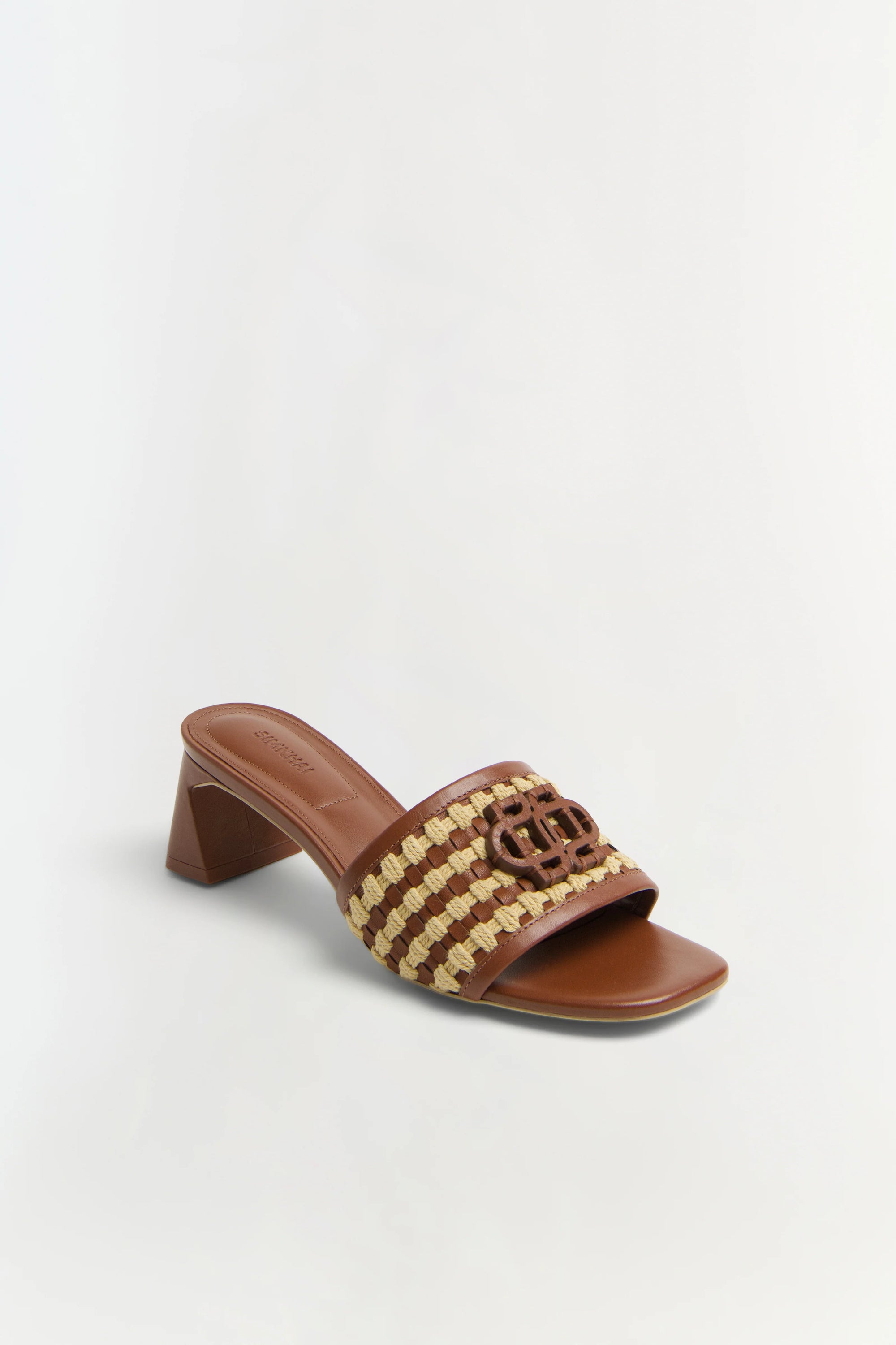 Brown sandal with woven design and wooden block heel on a light gray background
