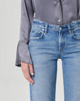 Person wearing a gray shirt and blue jeans on a light gray background
