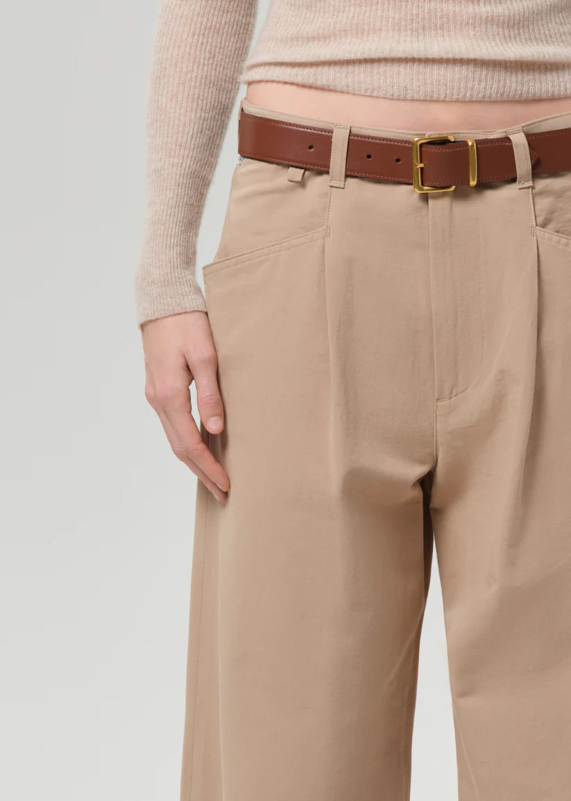 Beige pants with a brown belt on a plain background