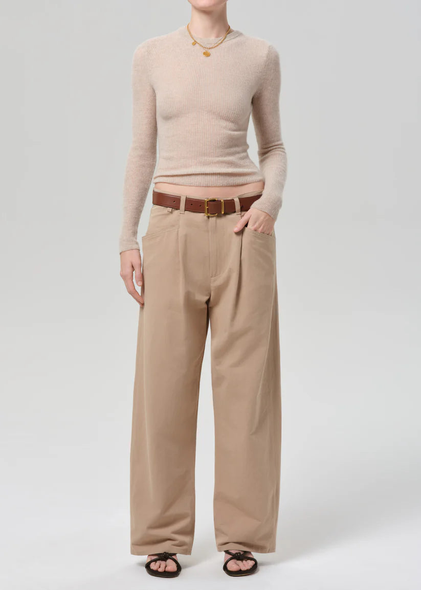 Person wearing a beige sweater and tan pants on a white background
