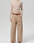 Person wearing a beige sweater and tan pants on a white background