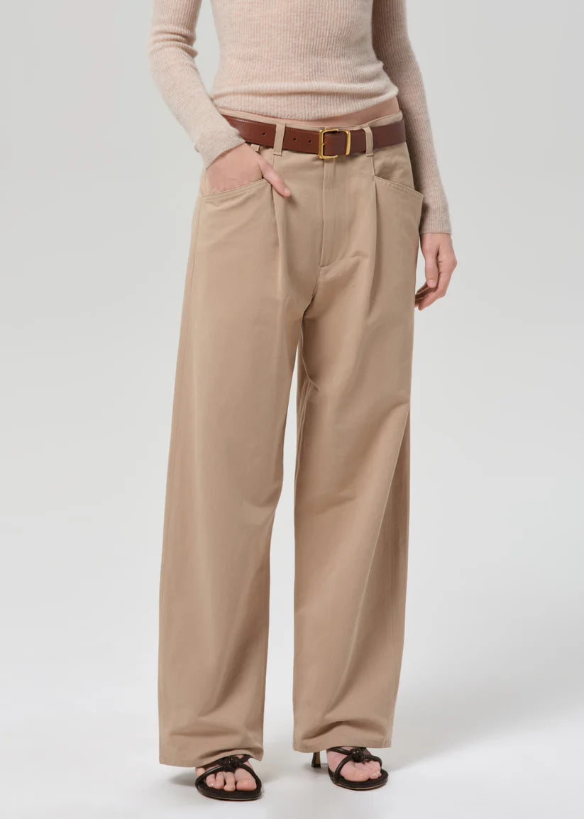 Person wearing beige wide-leg pants with a brown belt on a white background