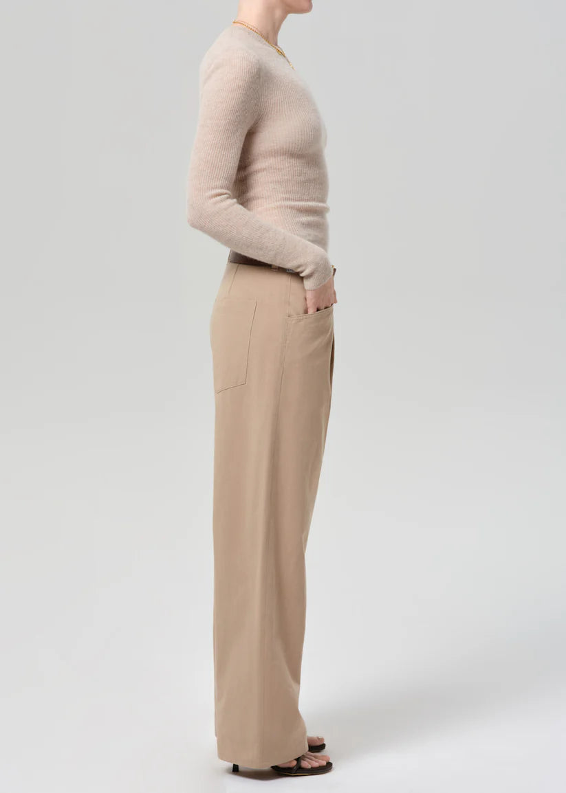 Person wearing a beige sweater and tan pants on a white background
