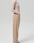 Person wearing a beige sweater and tan pants on a white background