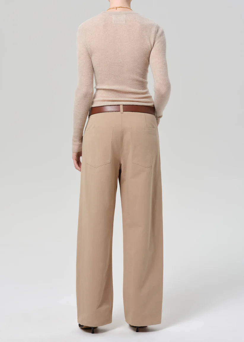 Person wearing a beige sweater and tan pants on a white background