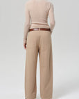 Person wearing a beige sweater and tan pants on a white background