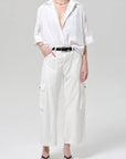 Person wearing a white shirt and wide-leg pants on a plain background