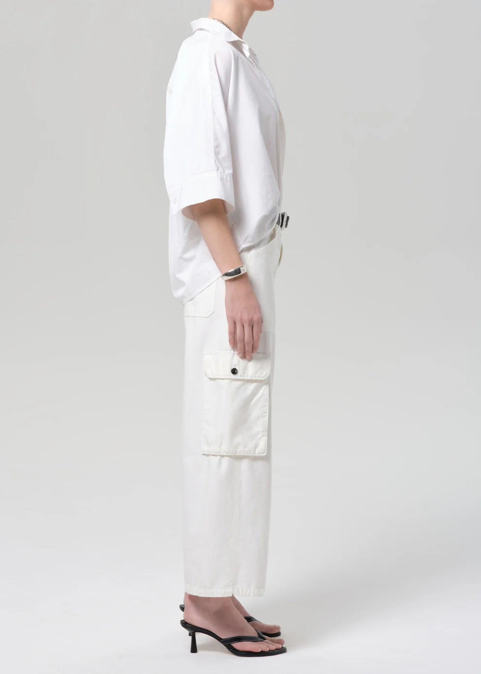 Person wearing a white outfit with cargo pants on a plain background