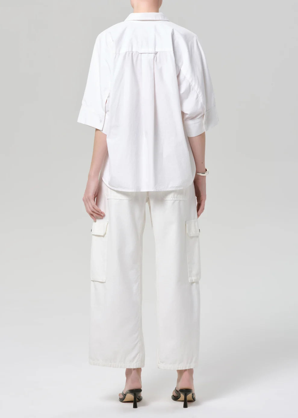 Person wearing a white outfit with a shirt and pants on a plain background