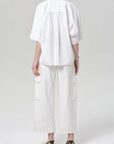 Person wearing a white outfit with a shirt and pants on a plain background