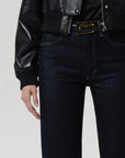 Person wearing a black leather jacket and dark jeans on a light gray background