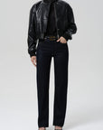Person wearing a black leather jacket, black turtleneck, black jeans, and black shoes on a white background