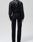 Person wearing a black leather jacket and dark jeans on a white background