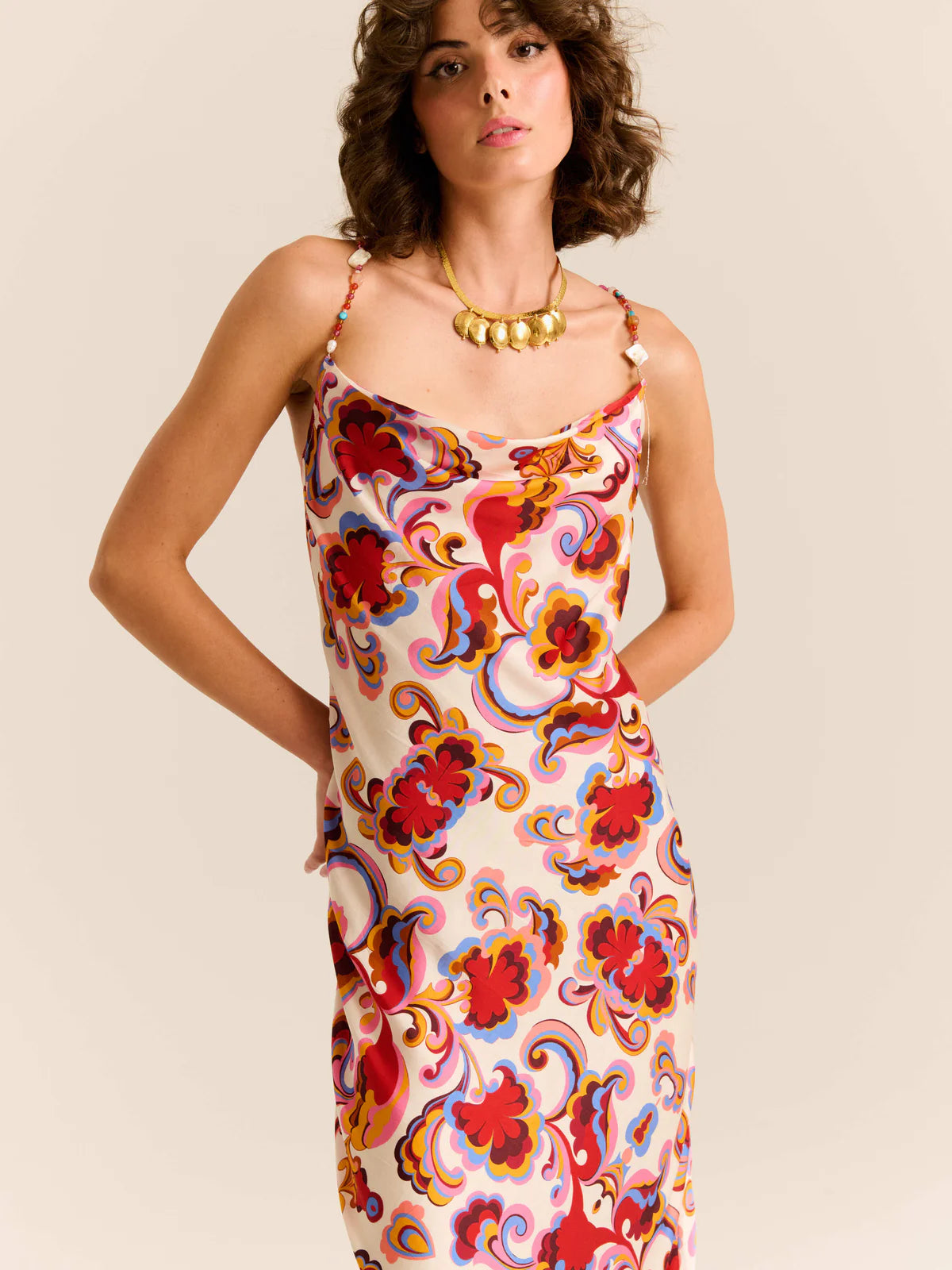Woman wearing a colorful floral dress against a beige background