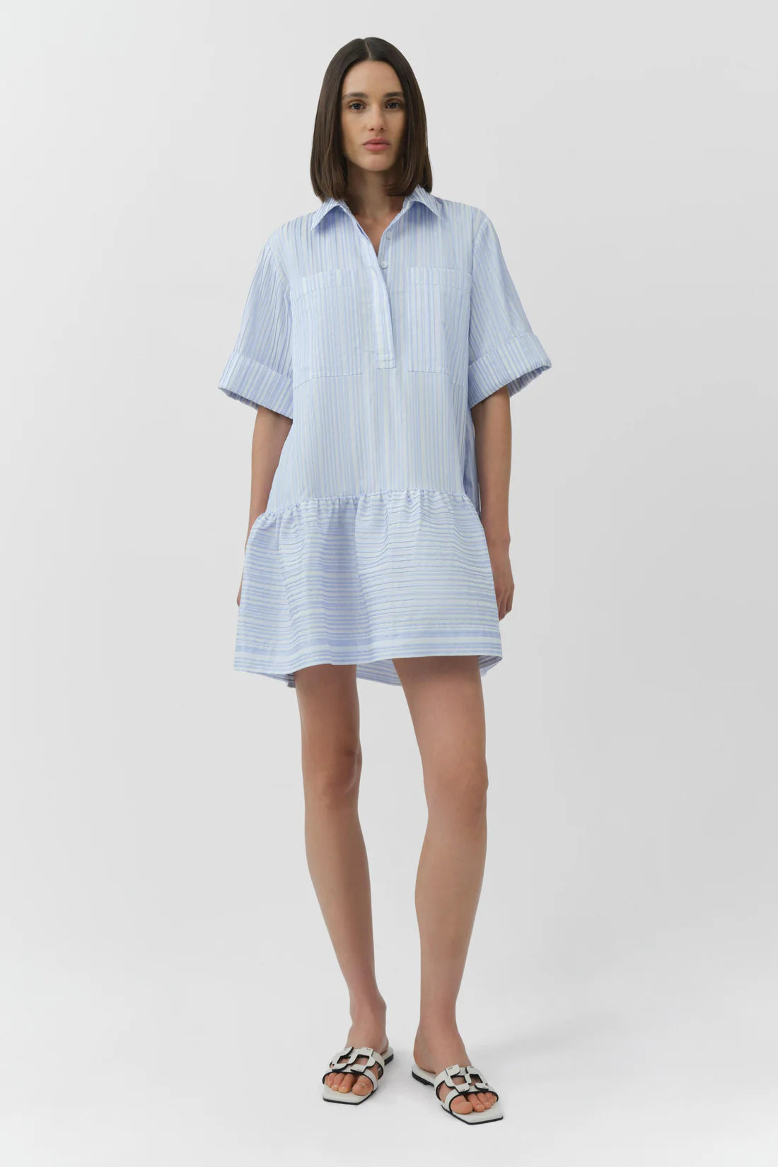 Woman wearing a light blue and white striped dress on a white background
