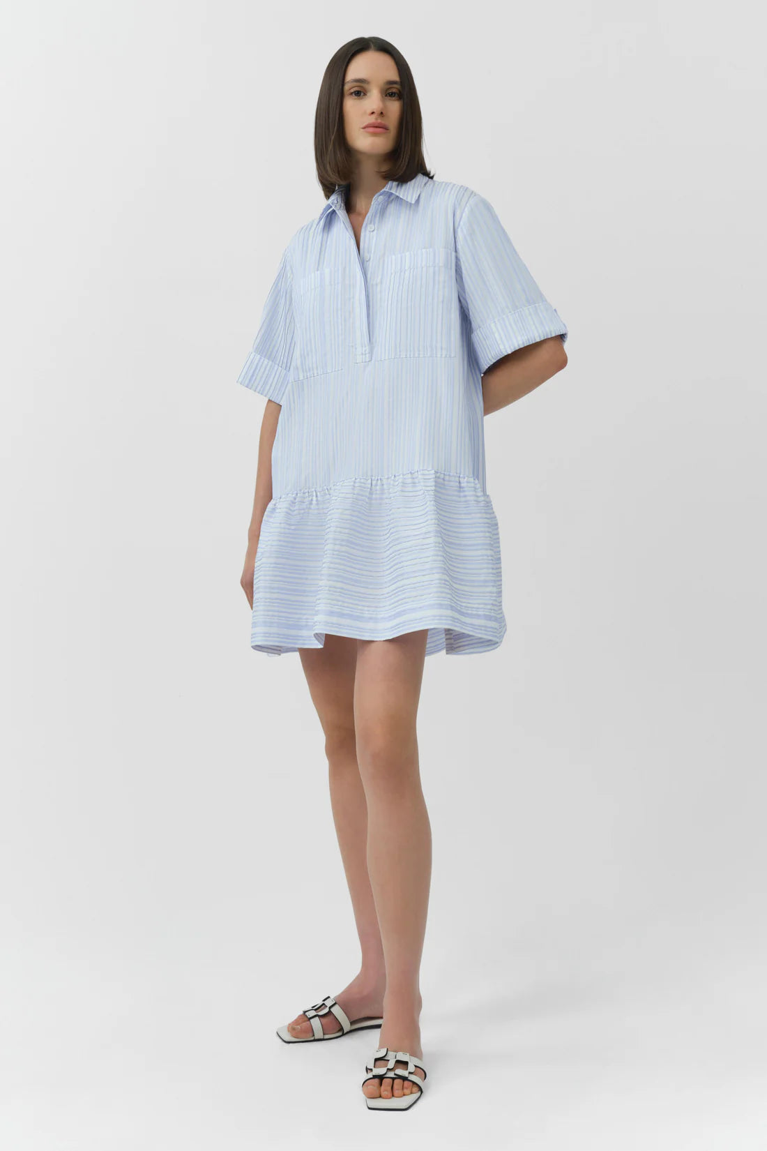 Woman wearing a light blue striped dress on a white background