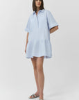 Woman wearing a light blue striped dress on a white background