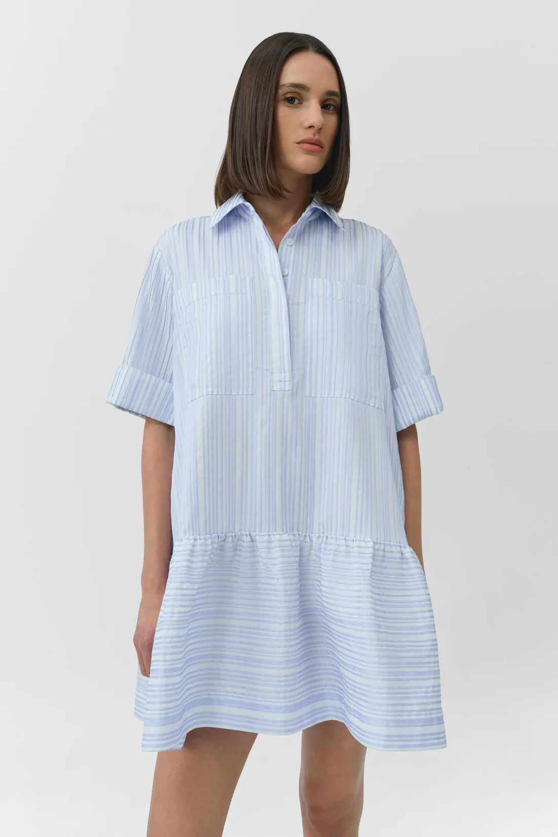 Woman wearing a light blue and white striped dress on a plain background