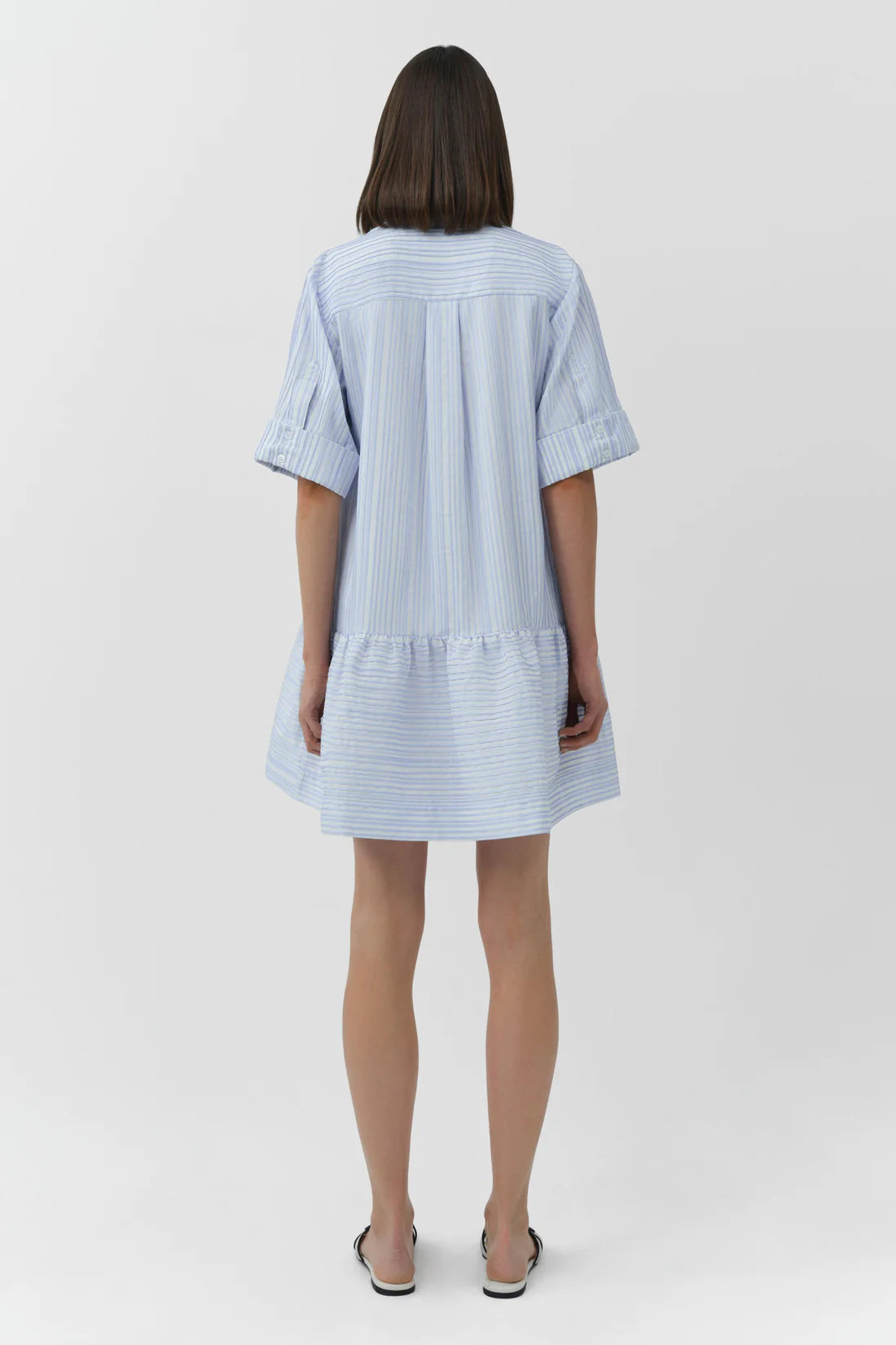 Woman wearing a light blue striped dress on a white background
