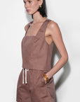 Woman wearing a brown sleeveless top and shorts set against a white background